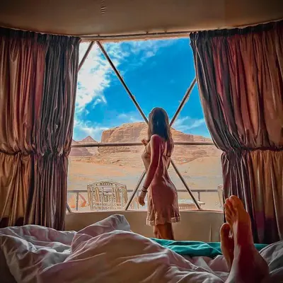 a woman standing in a window looking out at the desert at Wadi Rum Relaxation Camp in Wadi Rum