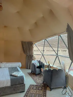 a woman sitting in a chair in a room with a window at Wadi Rum Relaxation Camp in Wadi Rum