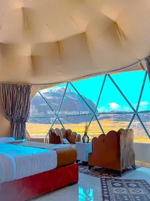 a room with two beds and a large window at Wadi Rum Relaxation Camp in Wadi Rum