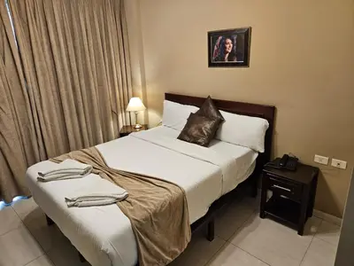 a hotel room with a large bed with white sheets at Saint John Hotel in Madaba