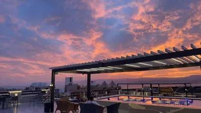 a sunset on the roof of a building with a pool at Mass Paradise Hotel in Aqaba