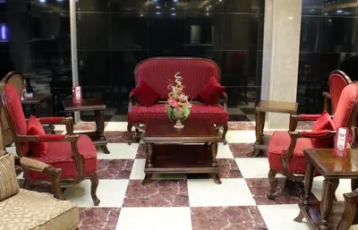 a room with red chairs and a table with a vase at Nahas Plaza in Irbid