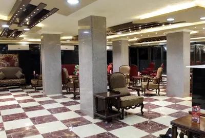 a lobby with chairs and tables and a checkered floor at Nahas Plaza in Irbid