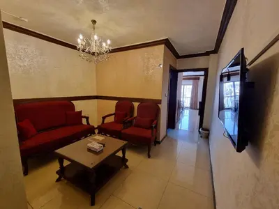 a waiting room with chairs and a table and a tv at Nahas Plaza in Irbid