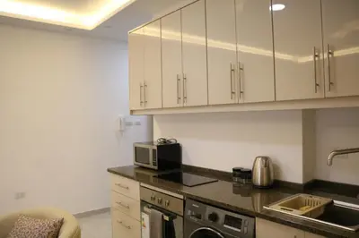 a kitchen with white cabinets and a microwave at Amazing one Bedroom Apartment in Amman Elwebdah 7 in Amman