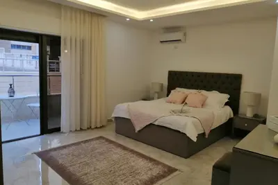 a bedroom with a bed with pink pillows on it at Amazing one Bedroom Apartment in Amman Elwebdah 3 in Amman