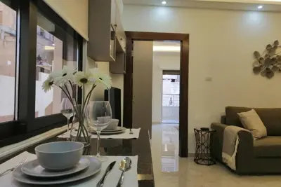 a living room with a table with plates and flowers at Amazing one Bedroom Apartment in Amman Elwebdah 3 in Amman