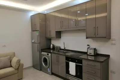 a kitchen with brown cabinets and a washer and dryer at Amazing one Bedroom Apartment in Amman Elwebdah 3 in Amman