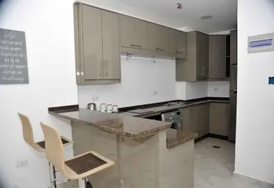 a kitchen with a counter and some chairs in it at Amazing one Bedroom Apartment in Amman Elwebdah 2 in Amman