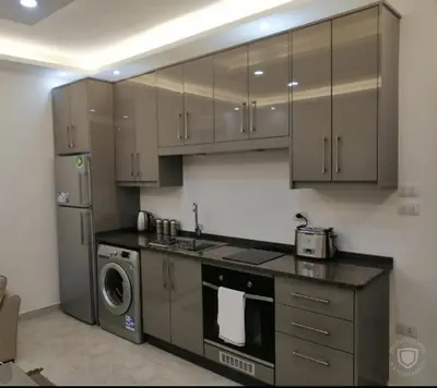 a kitchen with brown cabinets and a washer and dryer at Amazing one Bedroom Apartment in Amman Elwebdah 1 in Amman
