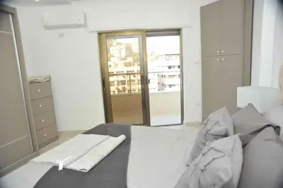 a bedroom with a bed and a large window at Amazing one Bedroom Apartment in Amman Elwebdah 4 in Amman
