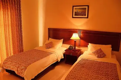 a hotel room with two beds and a lamp at Mosaic City Hotel in Madaba
