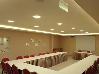 a conference room with red chairs and tables and a whiteboard at Mosaic City Hotel in Madaba