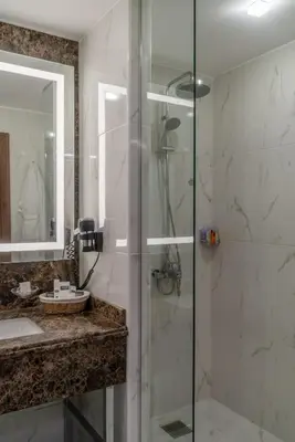 a bathroom with a glass shower and a sink at Landmark Amman Hotel & Conference Center in Amman