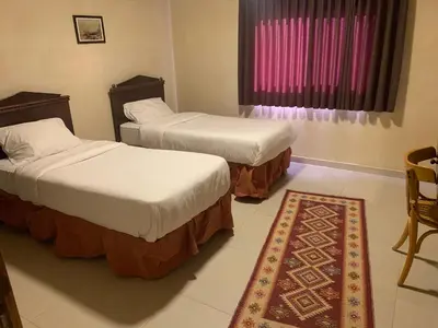 two beds in a room with a rug and a window at Nonna Aisha B&B in Wadi Musa