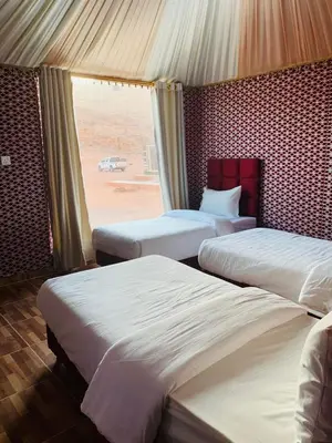 two beds in a room with a view of the desert at Luxury Color Camp in Wadi Rum