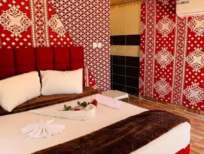 a bedroom with a bed with red and white wallpaper at Luxury Color Camp in Wadi Rum
