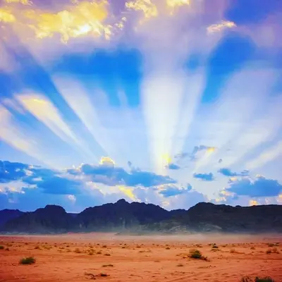 a rainbow in the sky over a desert with mountains at Maraheb Luxury camp in Wadi Rum