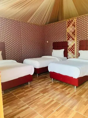 three beds in a room with wooden floors at Maraheb Luxury camp in Wadi Rum