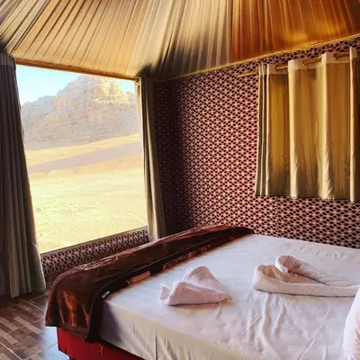 a bed in a room with a large window at Maraheb Luxury camp in Wadi Rum