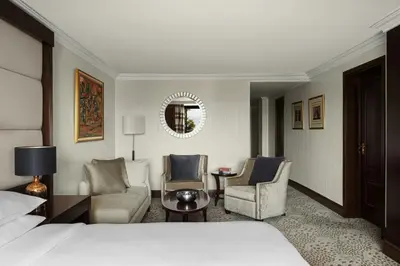 a hotel room with a bed and chairs and a mirror at Dead Sea Marriott Resort & Spa in Sowayma