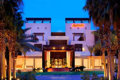 a building with palm trees in front of it at Dead Sea Marriott Resort & Spa in Sowayma