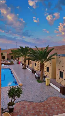 a resort with a pool and palm trees in the desert at Bait Alaqaba dive center & resort in Aqaba