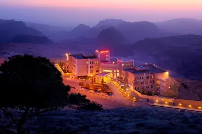 a group of buildings on a mountain at night at Petra Marriott Hotel in Wadi Musa