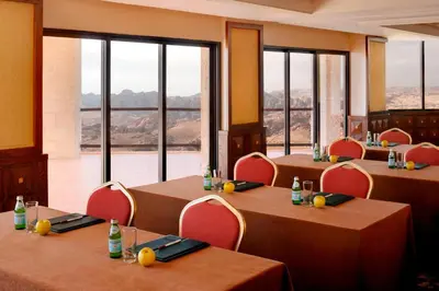 a dining room with tables and chairs and windows at Petra Marriott Hotel in Wadi Musa