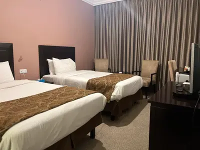 a hotel room with two beds and a desk at Shepherd Hotel in Amman