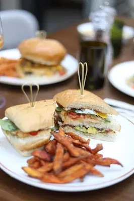 a plate with a sandwich and french fries on a table at Shepherd Hotel in Amman