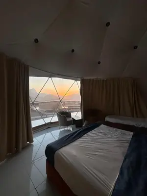 a bedroom with a large bed and a large window at Bubbles Desert Camp Jeep Tours in Wadi Rum