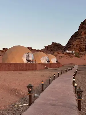 a row of tents in the desert with a sidewalk at Bubbles Desert Camp Jeep Tours in Wadi Rum