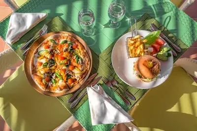 a table with two plates of food and a pizza at Grand Tala Bay Resort, Aqaba in Aqaba