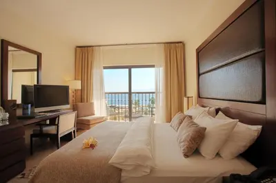 a bedroom with a large bed with a desk and a window at Grand Tala Bay Resort, Aqaba in Aqaba