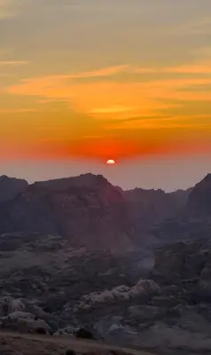 a sunset over the mountains in the desert at Omar Apartment in Wadi Musa