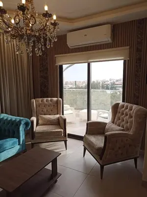 a living room with two chairs and a chandelier at AlQimah Hotel Apartments in Amman
