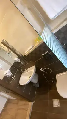 a bathroom with a white toilet and a sink at AlQimah Hotel Apartments in Amman