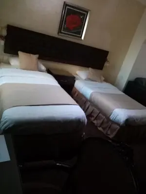 two twin beds in a room with a chair at الفارس الوسيم للشقق الفندقيه in Amman