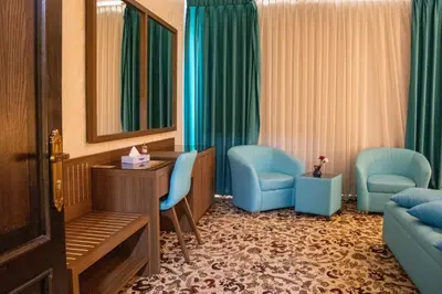 a hotel room with blue chairs and a mirror at The Castle Hotel in Amman