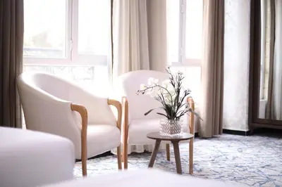 a room with two chairs and a table with a vase of flowers at The Castle Hotel in Amman