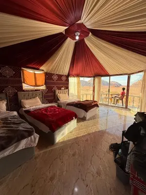 a bedroom with three beds and a large tent at joy of life Camp in Wadi Rum