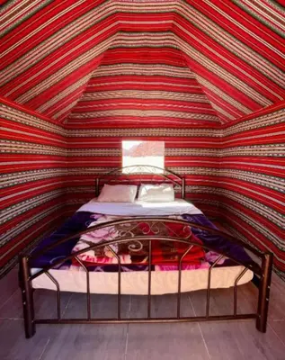 a bed in a room with a striped ceiling at joy of life Camp in Wadi Rum