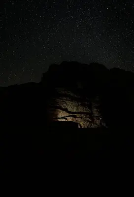 a mountain under a starry sky at night at joy of life Camp in Wadi Rum
