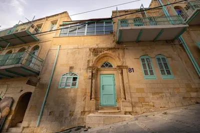 an old brick building with a green door and balcony at Jordan Heritage Madhafa in Al Salt