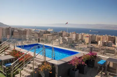 a swimming pool on top of a building with a city at Baity Boutique Hotel in Aqaba