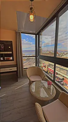 a living room with a table and a large window at Al-Naher Al-Khaled Hotel in Aqaba