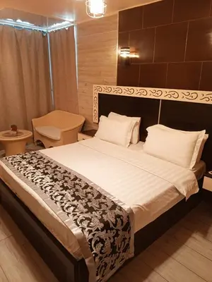 a bedroom with a large bed and a chair at Al-Naher Al-Khaled Hotel in Aqaba