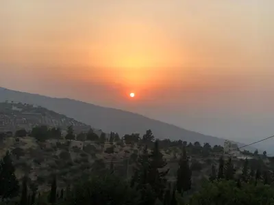 a sunset in the mountains with the sun setting at Sultana Farm - Private Pool Villa near Amman in Bayyūḑah