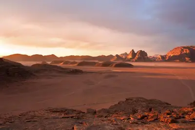 a desert with rocks and mountains in the background at Abdullah desert trips in Wadi Rum